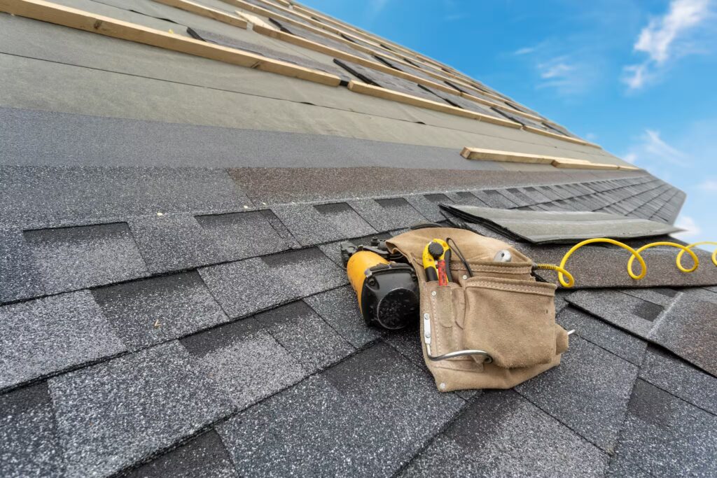 Close-up view of roofing tools and shingles on a house during a professional roof installation.
