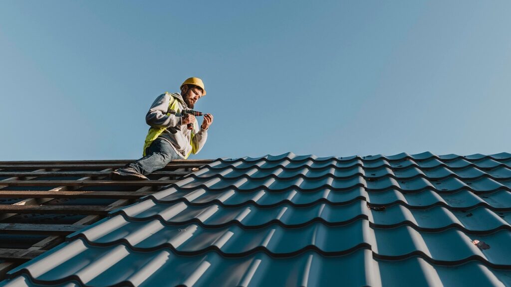 Professional roofer installing metal roofing on a residential home during a roof replacement project in Stoughton, WI.